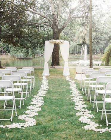 Patty's ceremony setup in a park: rows of white folding chairs along a petal-lined aisle