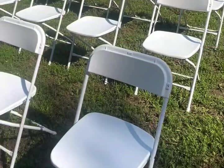 Rows of white folding chairs set on a lawn for a ceremony